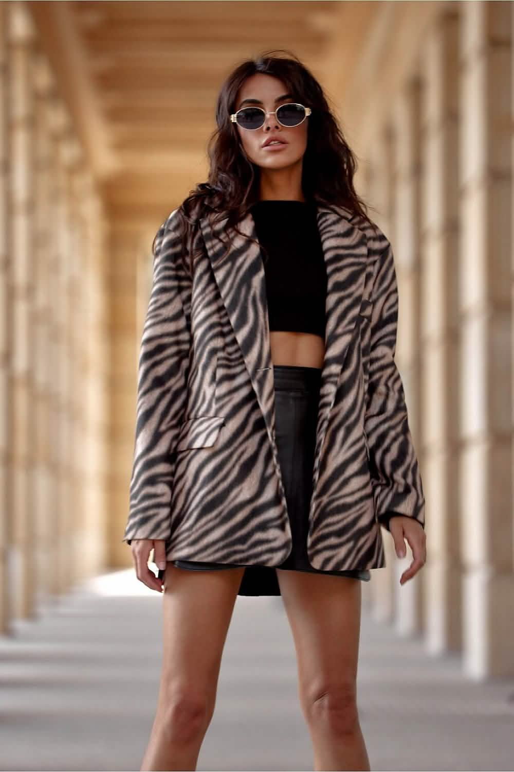 Zebra-print faux fur coat worn over a black crop top and mini skirt.