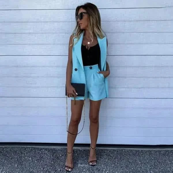 Stylish turquoise shorts suit paired with a black top and strappy sandals.